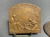 an antique brass plaque with a woman and child on it next to a penny