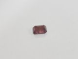 a pink tourmaline stone on a white surface