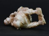 an antique ivory figurine of a baby laying on its back