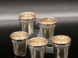 four silver shot glasses sitting on top of a tray on a table