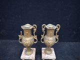 pair of antique brass vases on marble bases on a black background