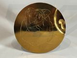 a gold plate with a picture of a woman on it
