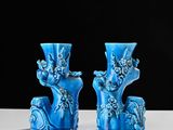 two blue vases sitting on a table with a black background