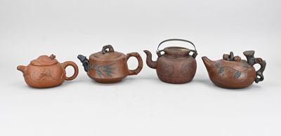 trois petites théières et une théière posées sur une surface blanche