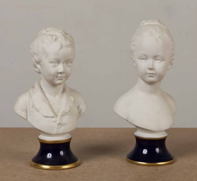 paire de bustes en porcelaine blanche représentant un garçon et une fille, posés sur des socles noirs