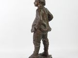 bronze statue of a man standing on a base with his hands in his pockets
