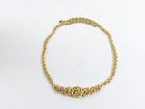 un bracelet en chaîne dorée orné d'un motif de nœud sur fond blanc