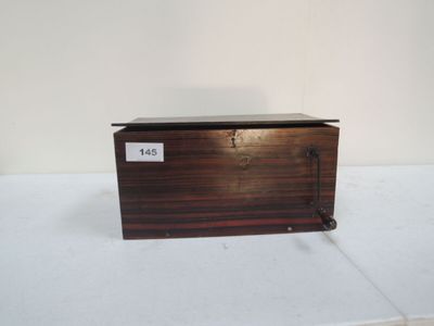 une vieille boîte en bois, sur laquelle est accrochée une étiquette, posée sur une table