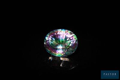 un gros plan d'un diamant aux couleurs de l'arc-en-ciel sur une surface noire