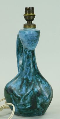 un vase bleu surmonté d'une lampe, à côté d'une paire de boucles d'oreilles