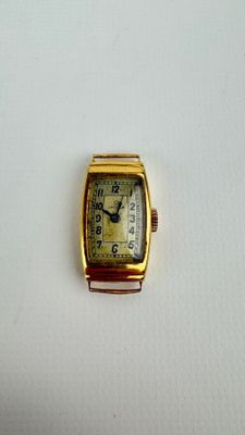 une petite montre en or avec un cadran blanc posée sur une surface blanche