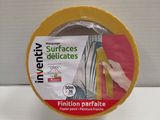 un ruban adhésif jaune sur une surface blanche, avec une main tenant un morceau de ruban adhésif