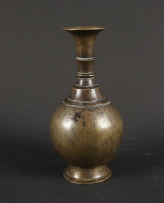 an antique brass vase on a black background with a dark background