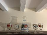 Des bouteilles et des verres sont posés sur une étagère dans une pièce.