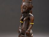 une photo représentant la statue d'un homme assis sur un tabouret