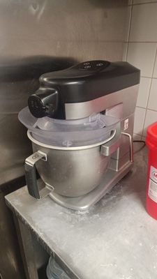 a red bucket sitting on a counter next to a mixer