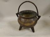 an old brass pot with a handle sitting on a white surface