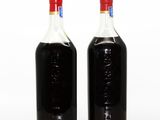 two bottles of black liquid sitting next to each other on a table