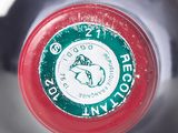 a close up of a bottle of wine with a red cap