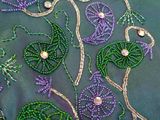 purple and green beaded flowers and leaves on a green cloth
