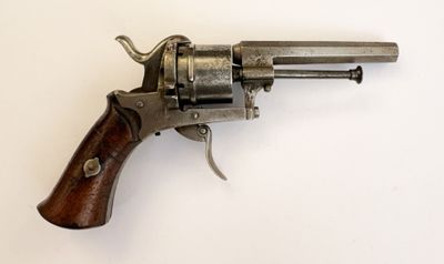un vieux revolver avec une poignée en bois sur une surface blanche
