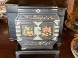 une petite armoire noire décorée de fleurs peintes