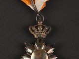 a silver medal with an orange ribbon and a crown on it