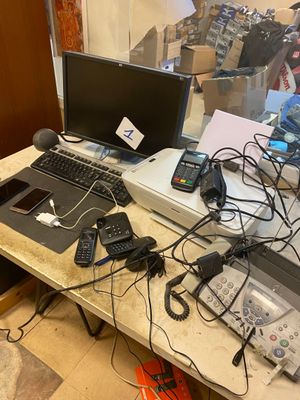 un bureau sur lequel se trouvent un ordinateur portable, une imprimante, un téléphone portable et d'autres appareils électroniques