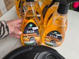 une personne tenant une bouteille de liquide vaisselle à côté de trois bouteilles de liquide vaisselle