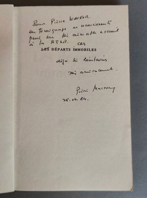 un livre ouvert, sur lequel est inscrit un poème manuscrit, posé sur une table