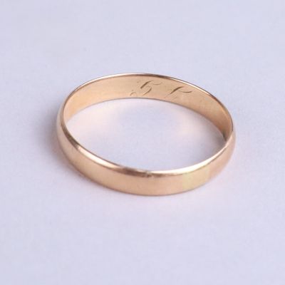 gros plan d'une bague en or sur une surface blanche