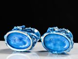 pair of blue glass vases sitting on top of a white table