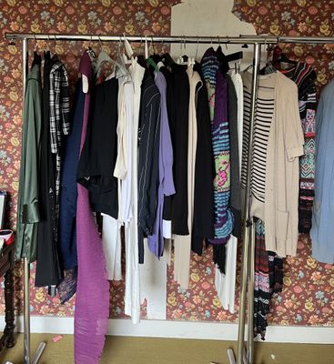 a rack of clothes in a room with a wallpapered wall