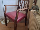 une chaise en bois avec une assise en cuir rouge, près d'un radiateur