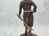 statue of a man with a sword and hat on a marble base