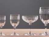 four wine glasses are lined up on a wooden table