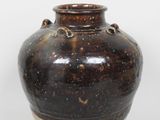 un vase marron posé sur une surface blanche