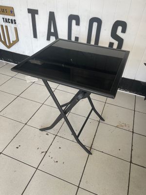 une table noire avec un plateau en verre, posée sur un sol carrelé