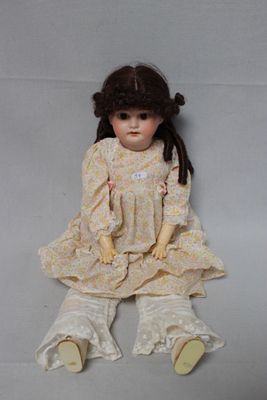 an image of a doll sitting on the ground with her legs crossed