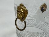 a glass vase with a gold lion head ring on it