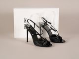 une paire de chaussures noires à talons hauts posée sur une boîte blanche