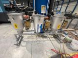 trois cuves en acier inoxydable posées sur une table dans un entrepôt