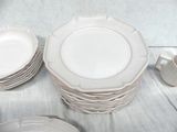 a lot of white plates and cups on a table