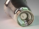 a close up of a silver pepper shaker on a white surface