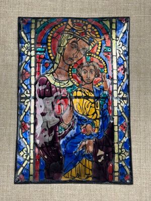un tableau représentant une femme tenant un enfant dans ses bras, encadré d'un vitrail