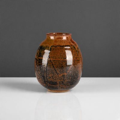 un vase marron posé sur une table blanche