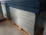 plusieurs piles de tôles d'acier empilées sur des palettes dans un entrepôt