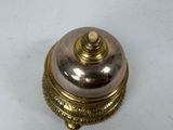 a silver plate with a gold lid on a white table