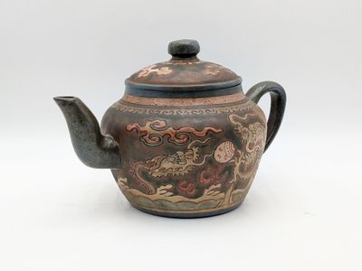 a brown teapot with a dragon design on it