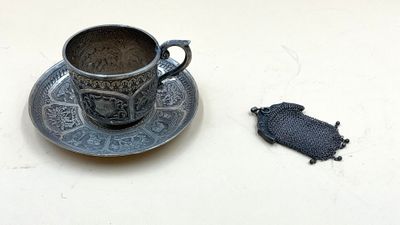une tasse et une soucoupe posées sur la table, à côté d'un morceau de tissu